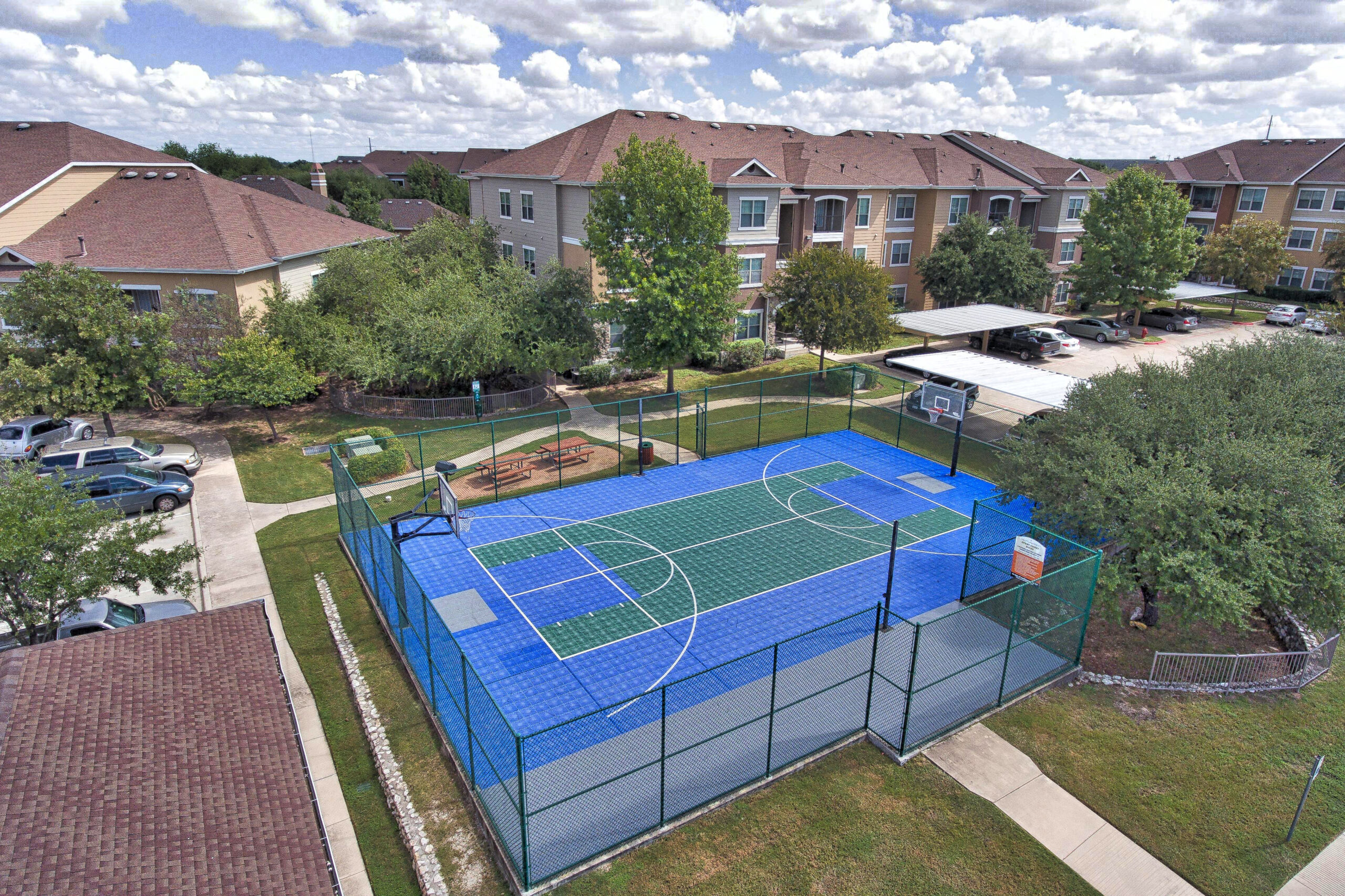 Shot of a Cypress Creek showing an aerial view of a blue and green basketball court with apartment buildings surrounding