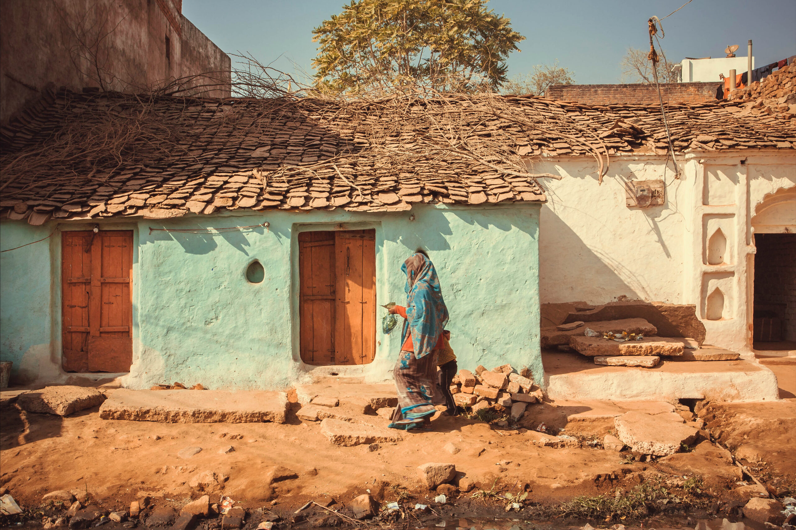 People walking past small traditional indian village house. Colorful buildings of rural area in India.