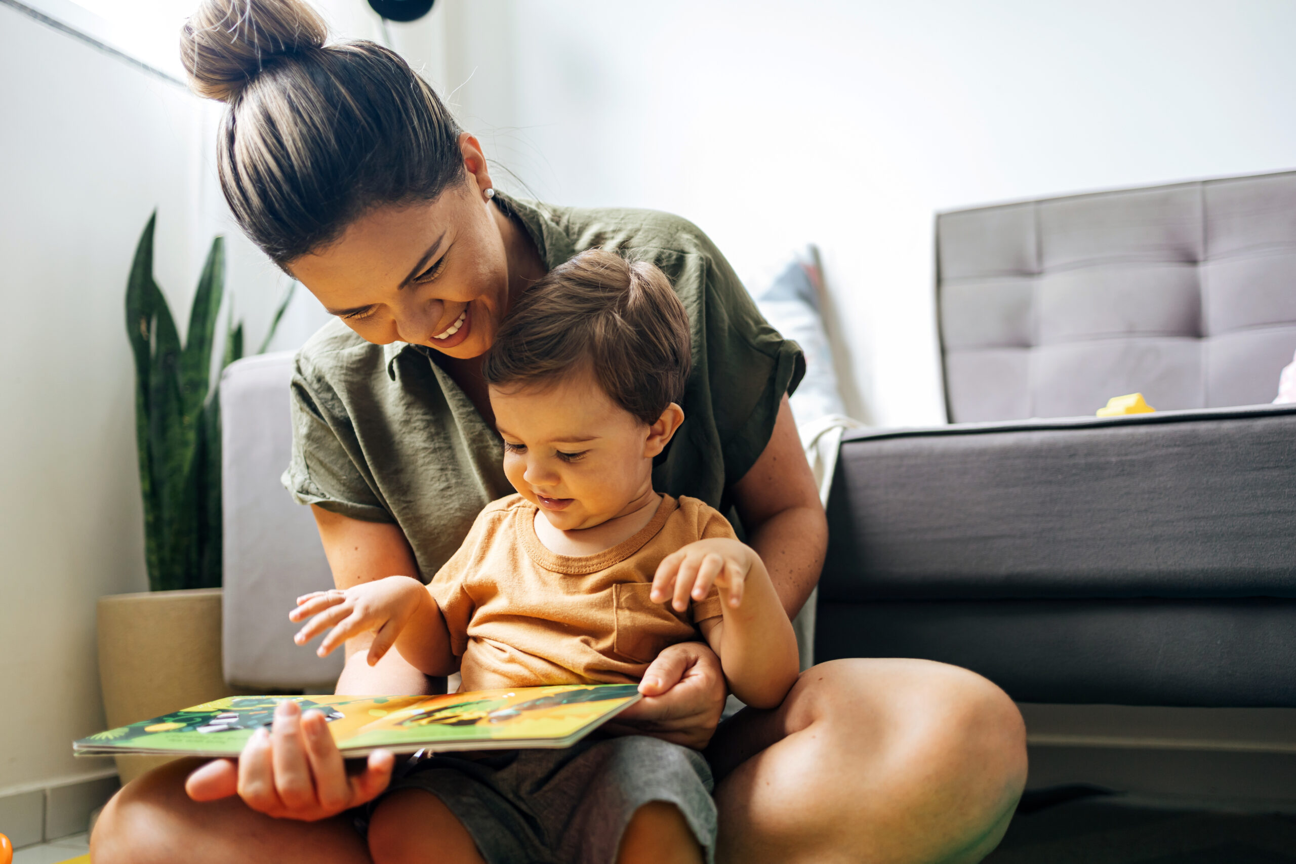 Mom reading a book with baby boy at home. Early age children education, development. Mother and child spending time together. Candid lifestyle.
